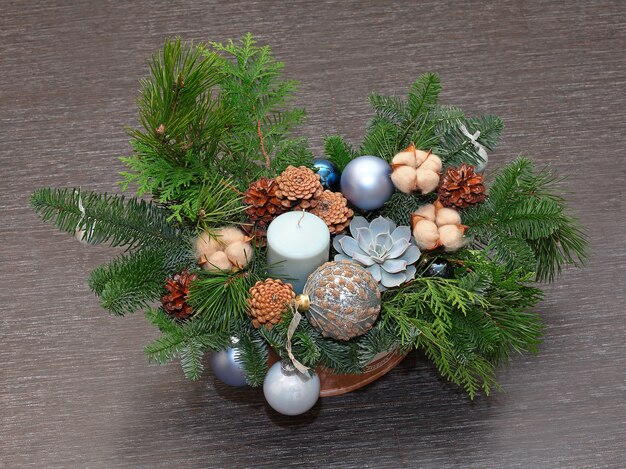 Composición navideña de ramas de pino, conos, algodón, bolas y vela. Fotografía de cerca. Sobre fondo oscuro