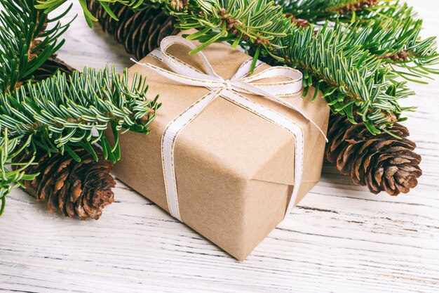 Composición navideña. Regalo de Navidad con piñas y ramas de abeto en madera.