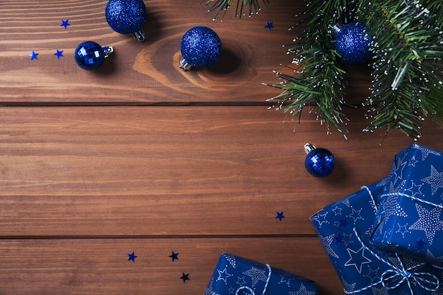 Composición navideña. Regalos, ramas de abeto, adornos azules en madera. Navidad, invierno, concepto de vacaciones de año nuevo. Endecha plana, vista superior, espacio de copia