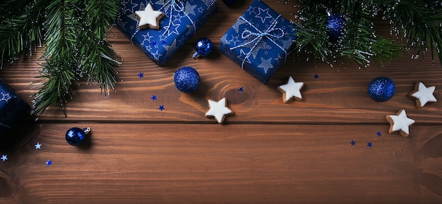 Composición navideña. Regalos, ramas de abeto, adornos azules sobre superficie de madera. Navidad, invierno, concepto de vacaciones de año nuevo. Endecha plana, vista superior, espacio de copia, banner largo