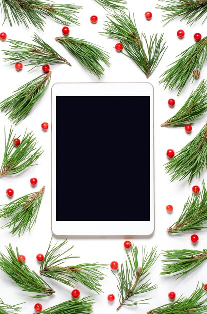 Composición navideña sobre un fondo blanco. Pantalla de tableta en blanco para texto o saludos. Endecha plana, copie el espacio.