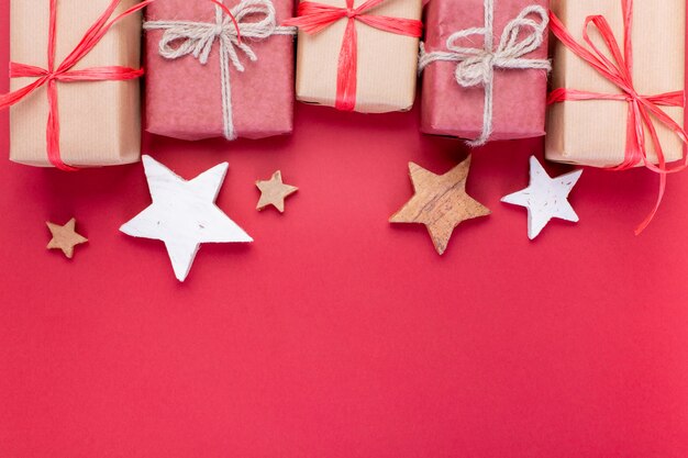 Composición navideña, tarjeta de felicitación. Decoraciones de Navidad rojo, estrellas y cajas de regalo sobre fondo rojo. Vista plana, vista superior, espacio para el texto.