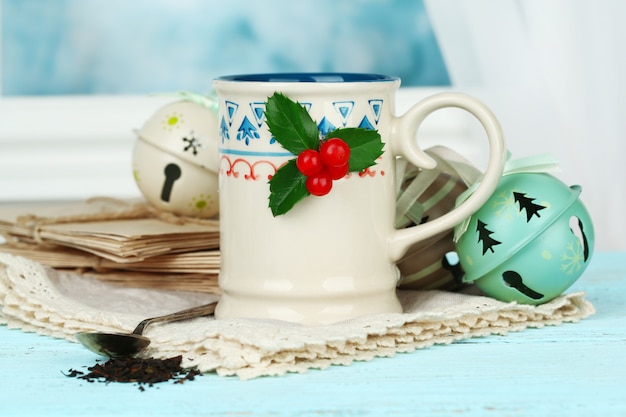 Composición navideña con taza de bebida caliente, sobre mesa de madera