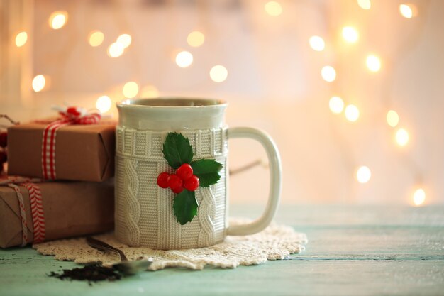 Composición navideña con taza de bebida caliente, sobre mesa de madera