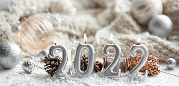 Composición navideña con velas en forma de números 2022 y detalles de decoración festiva sobre un fondo borroso.