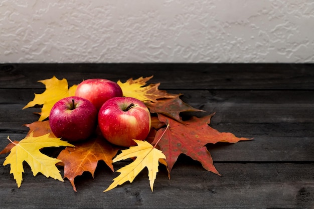 Composición otoñal de manzanas y hojas de arce sobre una mesa de madera