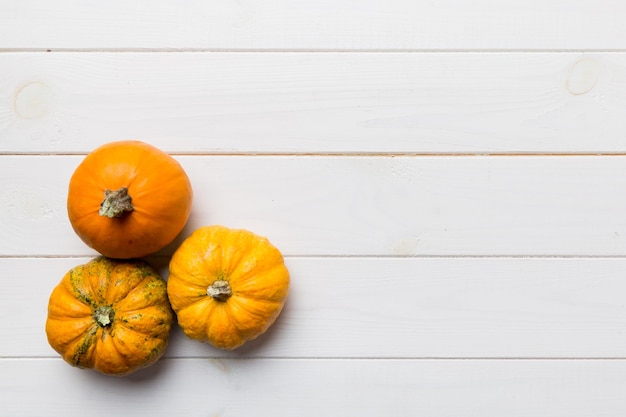 Composición otoñal de pequeñas calabazas naranjas sobre fondo de mesa de colores Concepto de otoño de Halloween y Acción de Gracias Fotografía plana de otoño Vista superior con espacio de copia