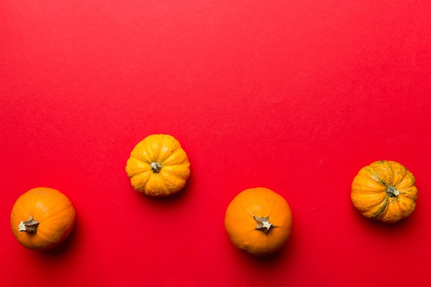 Composición otoñal de pequeñas calabazas naranjas sobre fondo de mesa de colores Concepto de otoño de Halloween y Acción de Gracias Fotografía plana de otoño Vista superior con espacio de copia