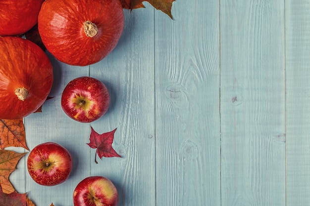 Composición de otoño con hojas de colores, manzanas y calabazas sobre superficie de madera