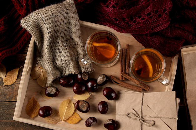 Composición de otoño con hojas de té amarillo caliente y libros sobre una mesa de madera marrón.