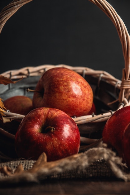 Composición de otoño con manzanas rojas frescas en una cesta de madera