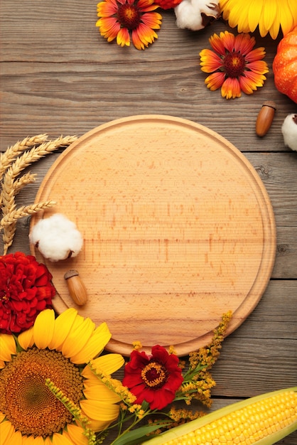 Composición de otoño. Marco de flores frescas sobre fondo de madera gris. Endecha plana, vista superior, espacio de copia. Día de Gracias. Foto vertical