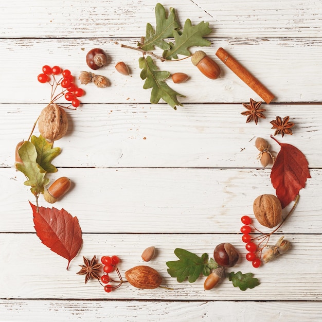 Composición de otoño de marco redondo Hojas secas, nueces y especias sobre una mesa de madera blanca