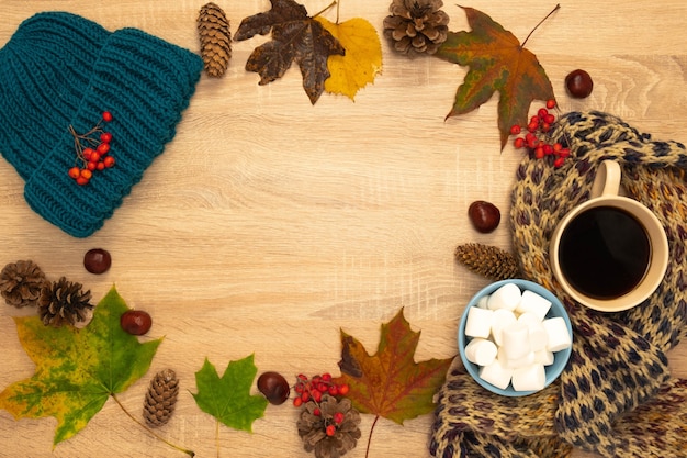Composición de otoño con sombrero, hojas y malvaviscos. Disparo desde arriba sobre un fondo de madera. Lugar para su texto.