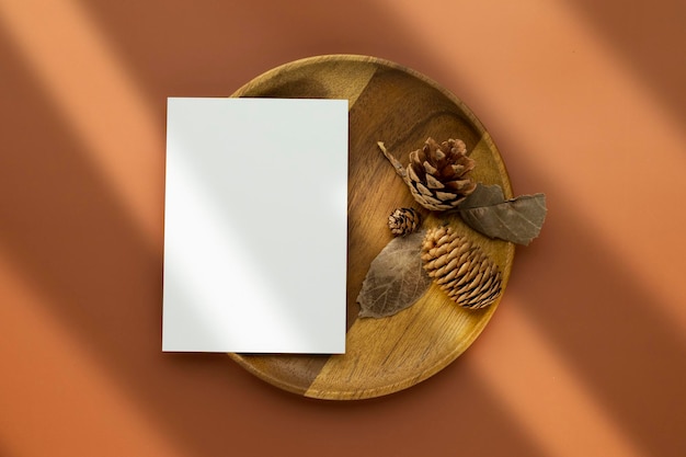 Composición de otoño Tarjetas de papel en blanco Mockup con hojas secas y piñas sobre fondo marrón Vista superior plana con espacio de copia