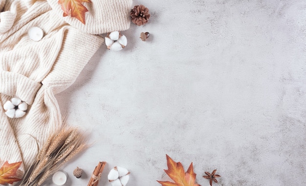 Composición de otoño Una taza de café, flores de algodón, hojas de otoño y suéter en piedra