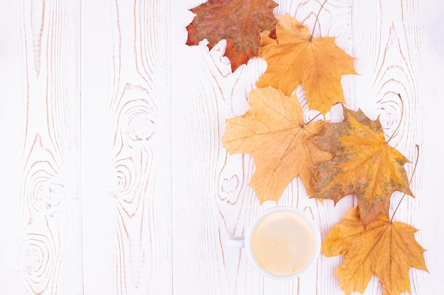 Composición de otoño con una taza de café hojas de arce secas amarillas de otoño sobre un fondo rústico de madera blanqueada Espacio de copia plana