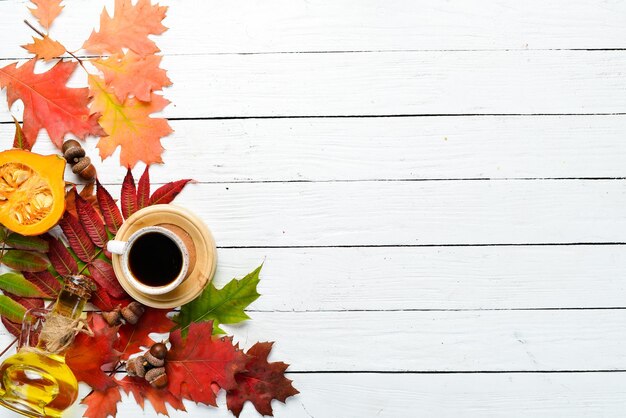 Composición de otoño Una taza de café y hojas de otoño de colores sobre un fondo blanco de madera Vista superior Espacio libre para el texto