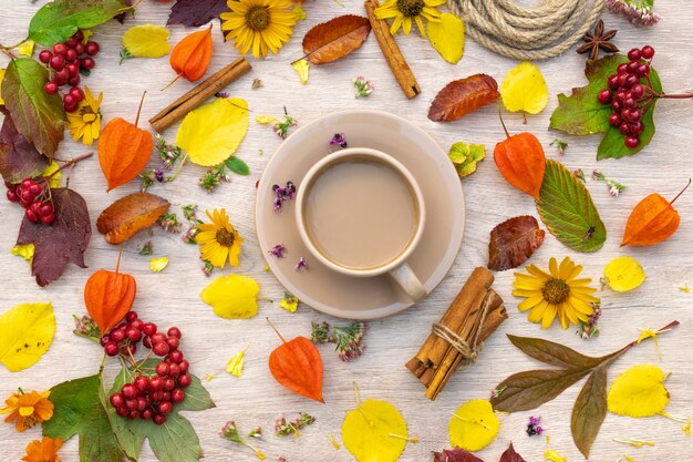 Composición de otoño taza de café sobre una mesa con flores y hojas, vista superior, imagen de fondo