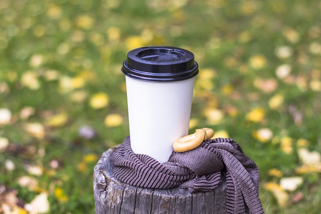 Composición de otoño. Taza de café en un tocón en el parque. Café para llevar entre las hojas de otoño.