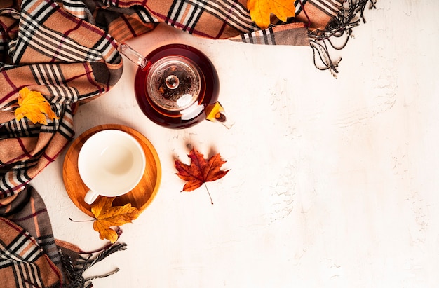 Composición de otoño. Una taza de té y tetera, bufanda, hojas de otoño. Endecha plana, vista superior, espacio de copia. Foto de alta calidad
