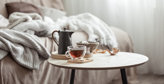 Composición de otoño con una taza de té, una tetera y detalles de decoración del hogar otoñal sobre un fondo borroso.