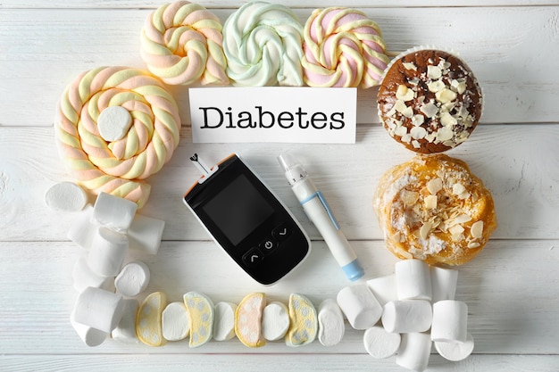 Composición con palabra Diabetes dulces y glucómetro digital sobre fondo de madera