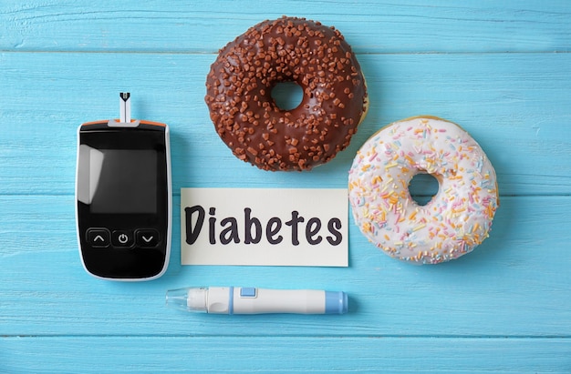 Composición con palabra Diabetes dulces y glucómetro digital sobre fondo de madera