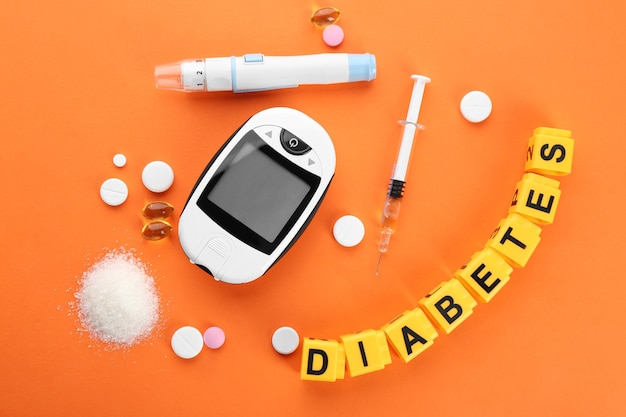 Composición con la palabra Medicamentos para la diabetes y glucómetro digital sobre fondo de color