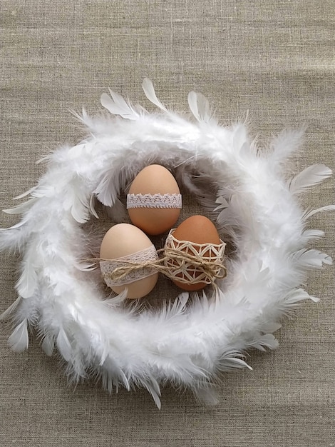 Composición de Pascua decorada con huevos de Pascua de encaje en corona de plumas blancas sobre fondo de lino. Concepto sin plástico y sin desperdicio