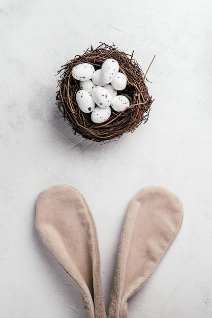 Composición de pascua de huevos de codorniz de punto blanco en nido marrón sobre fondo blanco conejito beige juguete orejas de pelo esponjoso