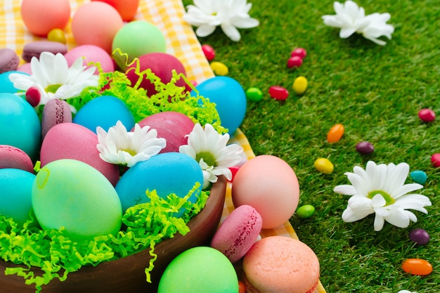 Composición de Pascua con huevos de colores y dulces brillantes sobre mantel amarillo