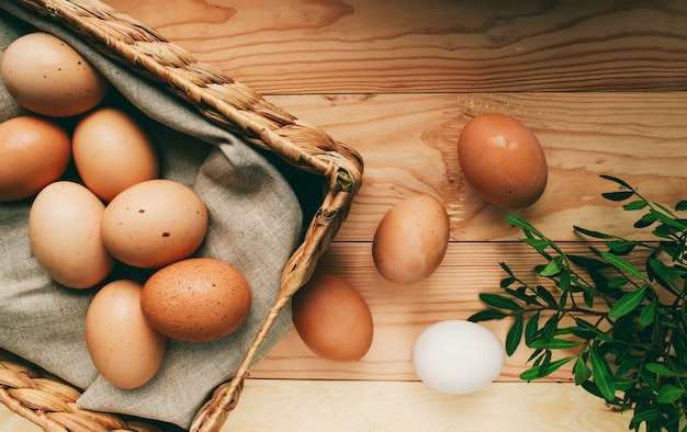 composición de Pascua Los huevos de Pascua se encuentran en una caja de huevos junto a las ramas verdes sobre un fondo claro de madera Foto del concepto de Pascua desde arriba