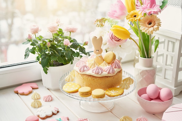 Composición de Pascua con huevos rosados, conejito de cerámica y flores en un jarrón
