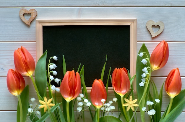 Composición de Pascua con pizarra enmarcada con flores de primavera, tulipanes y lirio