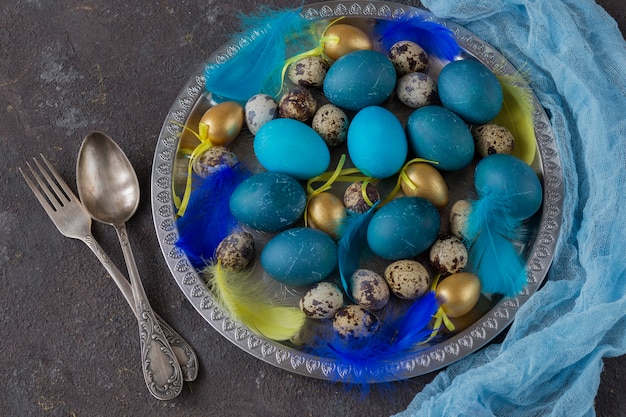 Composición de Pascua: en un plato de plata ponen huevos azules, huevos de oro, huevos de codorniz y plumas, y cubiertos