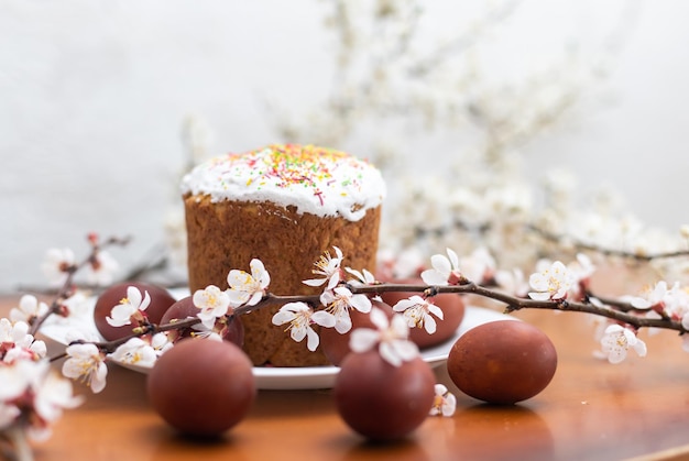 Composición de Pascua. Una rama de albaricoque floreciente, huevos pintados y un pastel de Pascua glaseado decorado con chispas de azúcar.