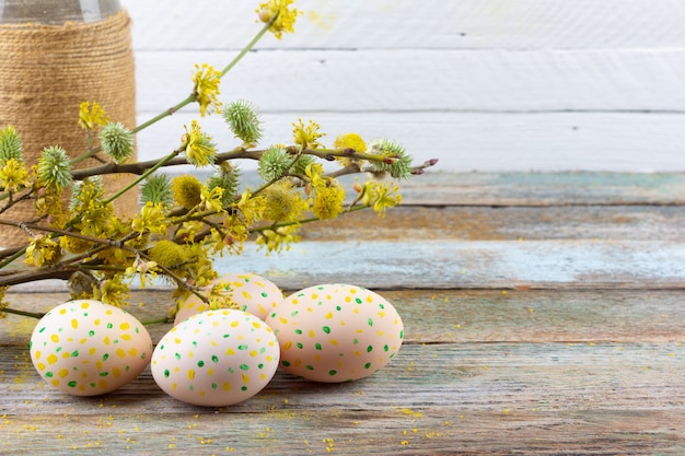 Composición de Pascua de ramitas florecientes de sauce, cornejo y huevos de Pascua con un patrón de puntos amarillos sobre un fondo retro de madera con una copia del primer plano del espacio