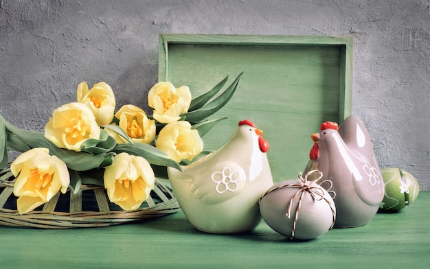 Composición de Pascua con tulipanes amarillos y gallinas de cerámica con huevos de Pascua,