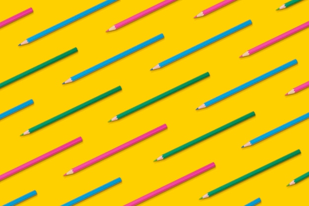 Composición de patrones de lápices de color en un fondo amarillo vista superior plana de vuelta a la escuela
