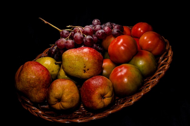 Composición de peras, tomates y uvas en una cesta.