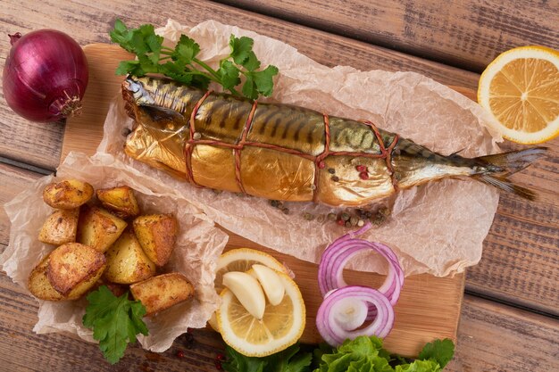 Composición de pescado caballa ahumado con guarnición de patatas cebollas verdes de limón servido en la vista superior de la placa de tablero de madera