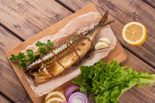 Composición de pescado caballa ahumado con guarnición de patatas cebollas verdes de limón servido en la vista superior de la placa de tablero de madera