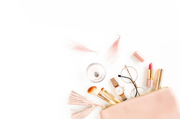 Composición plana con bolsa cosmética rosa con productos de maquillaje cosmético aislado sobre fondo blanco
