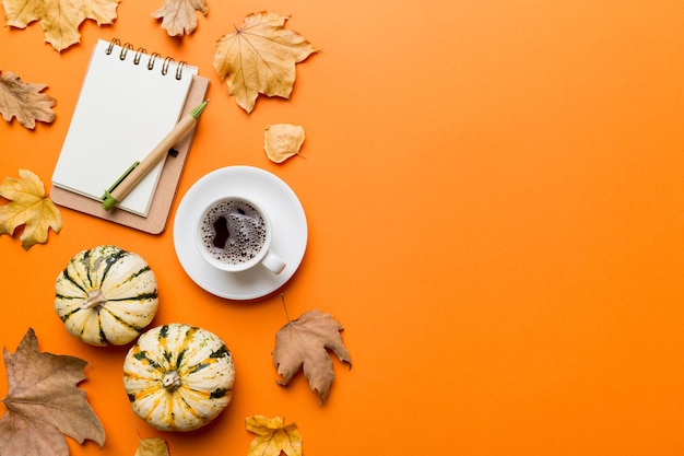 Composición plana con colorida taza de café de otoño y hojas en una vista superior de fondo de color