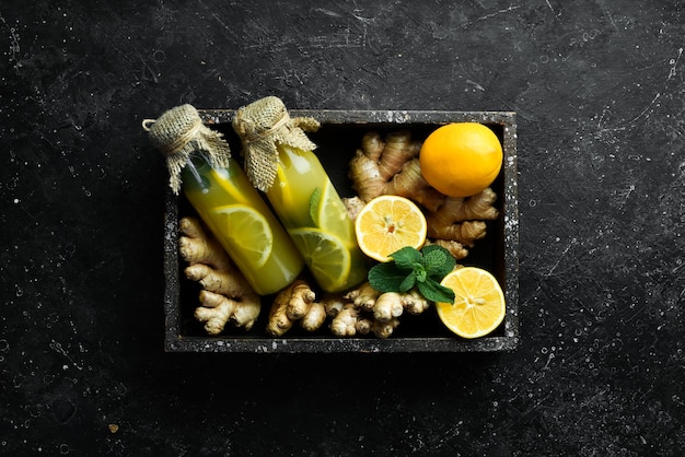 Composición plana con deliciosa limonada natural con limón, jengibre y hojas de menta Concepto de bebida saludable de vitamina sobre un fondo de piedra negra