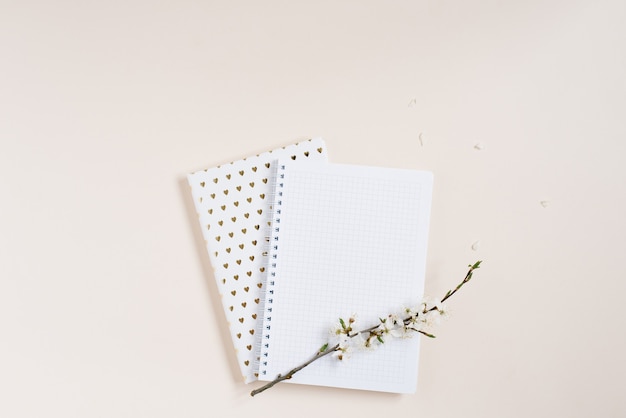 Composición plana endecha de flores de manzana blanca y Bloc de notas con un diseño de hoja en blanco en