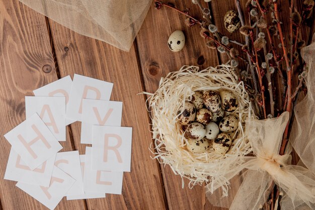 Composición plana endecha de huevos de codorniz y tarjeta con texto feliz Pascua en mesa de madera. Vista superior.