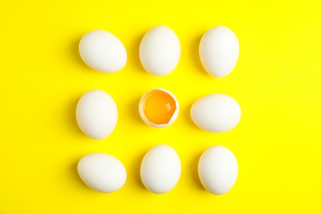 Composición plana con huevos de gallina y mitad con yema sobre fondo de color, espacio para texto