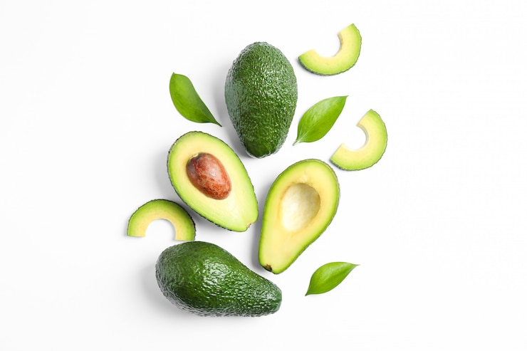 Foto composición plana laica con aguacates maduros y hojas en blanco